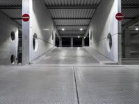 a long parking garage with metal roof and open doors with one way sign in the center