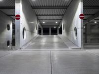 a long parking garage with metal roof and open doors with one way sign in the center