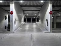 a long parking garage with metal roof and open doors with one way sign in the center