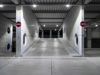 a long parking garage with metal roof and open doors with one way sign in the center