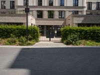 an entrance to a building with lots of trees and bushes in front of it on the ground