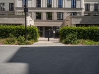 an entrance to a building with lots of trees and bushes in front of it on the ground