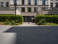 an entrance to a building with lots of trees and bushes in front of it on the ground