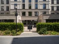 an entrance to a building with lots of trees and bushes in front of it on the ground