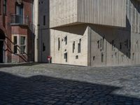 cobblestone driveway surrounded by modern buildings on sunny day with sun reflecting onto the windows