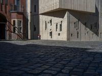 cobblestone driveway surrounded by modern buildings on sunny day with sun reflecting onto the windows