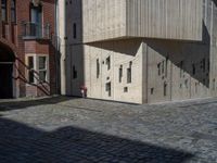 cobblestone driveway surrounded by modern buildings on sunny day with sun reflecting onto the windows