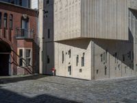 cobblestone driveway surrounded by modern buildings on sunny day with sun reflecting onto the windows