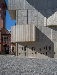 cobblestone driveway surrounded by modern buildings on sunny day with sun reflecting onto the windows