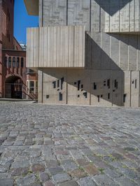 cobblestone driveway surrounded by modern buildings on sunny day with sun reflecting onto the windows