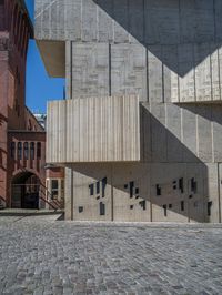 cobblestone driveway surrounded by modern buildings on sunny day with sun reflecting onto the windows