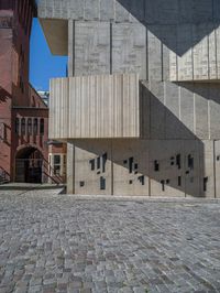 cobblestone driveway surrounded by modern buildings on sunny day with sun reflecting onto the windows