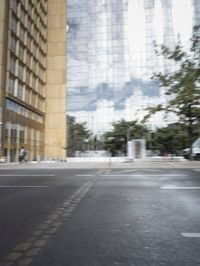 a red motorcycle with white wheels riding down the road near tall buildings with glass windows