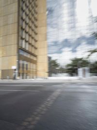a red motorcycle with white wheels riding down the road near tall buildings with glass windows