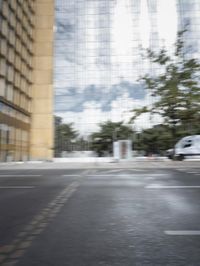 a red motorcycle with white wheels riding down the road near tall buildings with glass windows