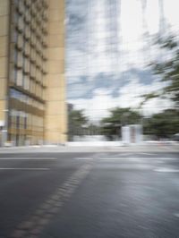 a red motorcycle with white wheels riding down the road near tall buildings with glass windows