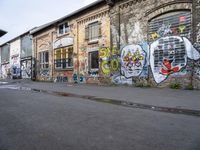 a mural in a back alley near a brick building with graffiti all over it's walls