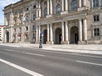 two streets leading to an old and white building with columns on both sides of the street