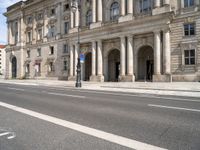 two streets leading to an old and white building with columns on both sides of the street