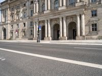 two streets leading to an old and white building with columns on both sides of the street