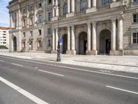 two streets leading to an old and white building with columns on both sides of the street