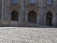 a man on an orange board in the courtyard with other people walking and riding bicycles behind him