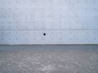 a white wall has a round window on it with two dark spots in the center