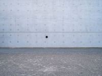 a white wall has a round window on it with two dark spots in the center