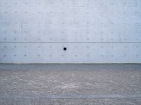 a white wall has a round window on it with two dark spots in the center