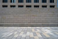 there is a large beige wall with windows along it and the sidewalk that separates the wall