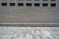 there is a large beige wall with windows along it and the sidewalk that separates the wall