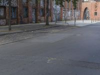 the person riding his skateboard down a quiet street in the daytime light and on the pavement there is graffiti