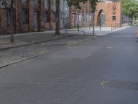 the person riding his skateboard down a quiet street in the daytime light and on the pavement there is graffiti