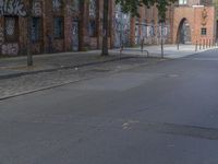 the person riding his skateboard down a quiet street in the daytime light and on the pavement there is graffiti