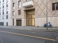 a motorcycle parked outside the doors of a building next to a sidewalk lined with tall building