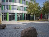 large boulders sit in front of a building with many glass doors and windows on one side