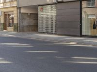 a man riding a motorcycle past a store on a street side walk on a sunny day