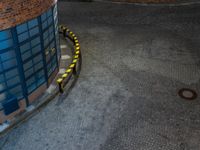 some dark blue windows in an industrial building with no one on the street to the right