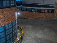 some dark blue windows in an industrial building with no one on the street to the right