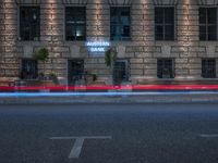 a traffic light streaks near a building with a sign reading auburn bank on it's side