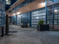 some dark blue windows in an industrial building with no one on the street to the right