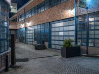 some dark blue windows in an industrial building with no one on the street to the right