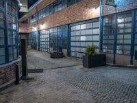 some dark blue windows in an industrial building with no one on the street to the right