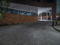 some dark blue windows in an industrial building with no one on the street to the right