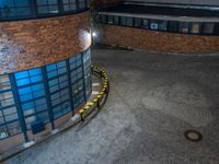 some dark blue windows in an industrial building with no one on the street to the right