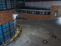 some dark blue windows in an industrial building with no one on the street to the right