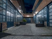 some dark blue windows in an industrial building with no one on the street to the right