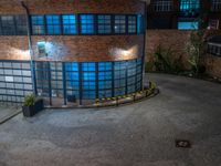 some dark blue windows in an industrial building with no one on the street to the right