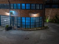 some dark blue windows in an industrial building with no one on the street to the right