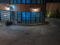 some dark blue windows in an industrial building with no one on the street to the right